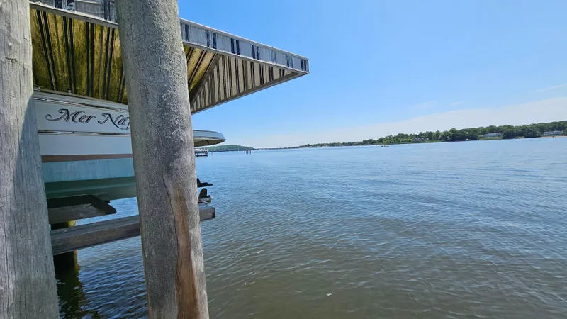 Slide: The Image of 2013 Chris-Craft Launch 22 boat docked by a serene lake under a clear blue sky. - 3