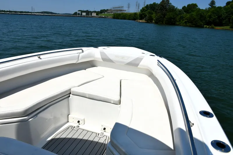 Slide: The Image of 2016 Boston Whaler 280 Outrage boat on a serene lake with lush green shoreline. - 21