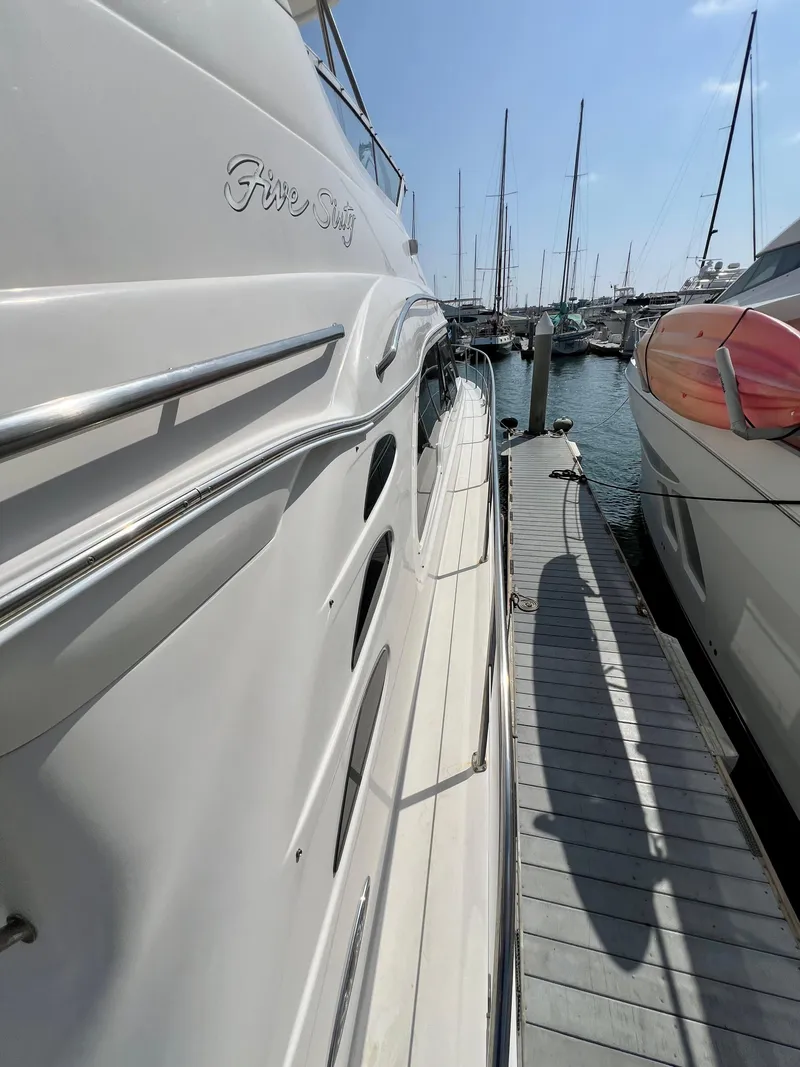 Slide: The Image of 2002 Sea Ray 560 Sedan Bridge yacht docked at marina under clear blue sky. - 13