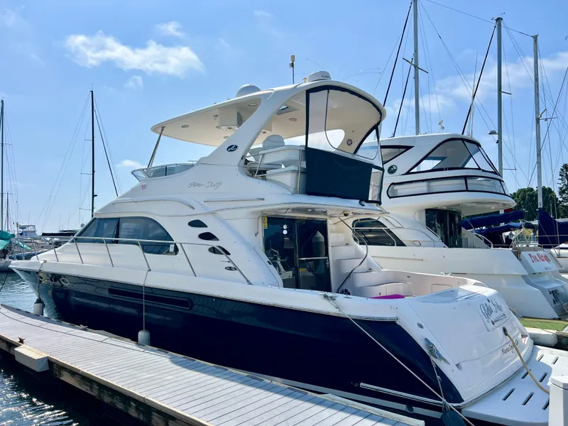 Slide: The Image of 2002 Sea Ray 560 Sedan Bridge yacht docked at marina under clear blue sky. - 5