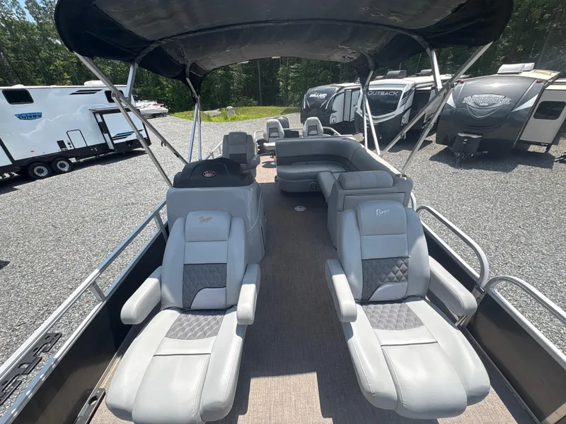 Slide: The Image of 2021 Ranger Reata 220F pontoon boat with plush seating and canopy, parked near RVs. - 21
