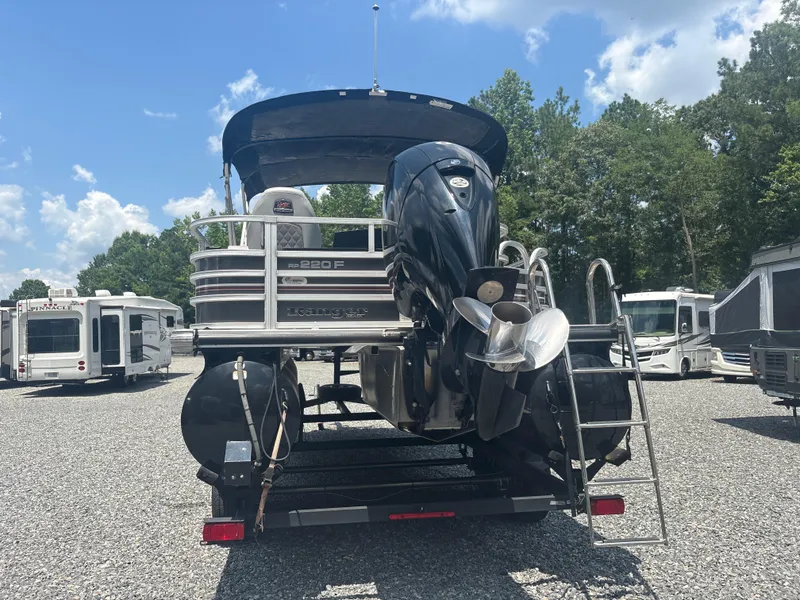 Slide: The Image of 2021 Ranger Reata 220F boat with motor, parked on gravel lot under blue sky. - 3