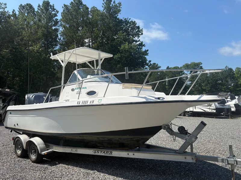 Slide: The Image of 2000 Key West 2300 Bluewater boat on trailer, parked outdoors with trees in background. - 5