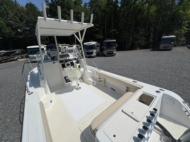 Slide: The Image of 2000 Key West 2300 Bluewater boat with center console, parked near RVs in a wooded area. - 9