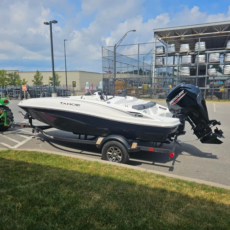 Slide: The Image of 2025 Tahoe T16 boat on trailer in parking lot, featuring Mercury outboard motor. - 2