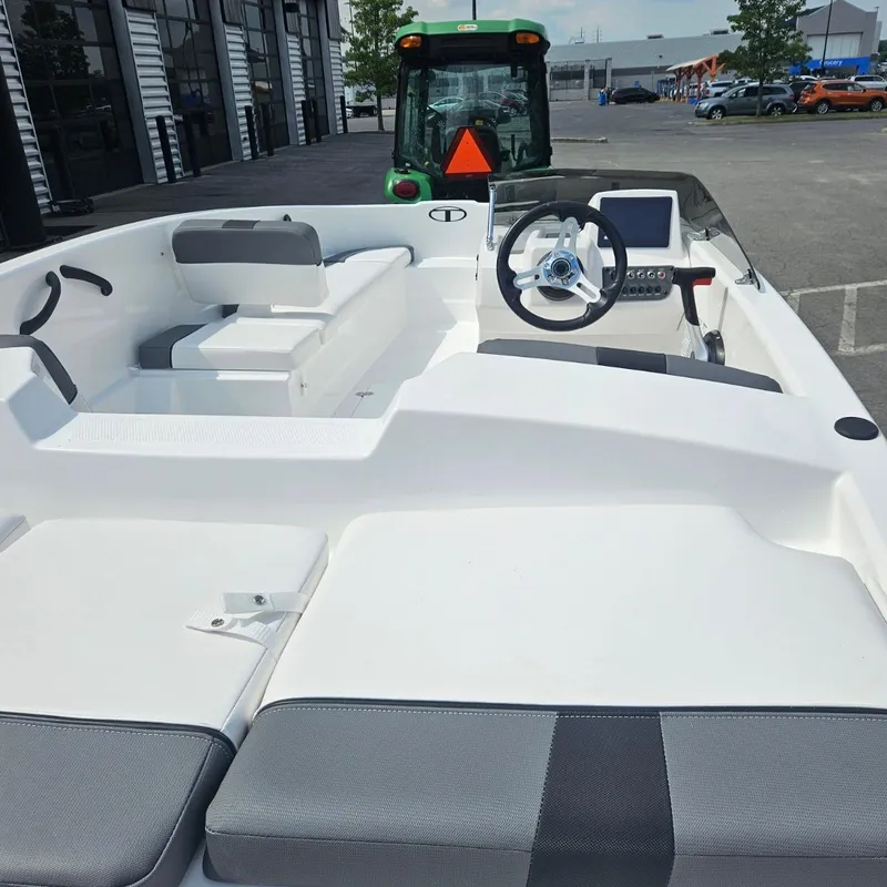 Slide: The Image of 2025 Tahoe T16 boat interior with steering wheel and seating, parked near a tractor. - 4
