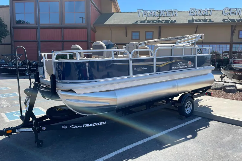 Slide: The Image of 2025 Sun Tracker Bass Buggy 18 DLX pontoon boat on trailer at dealership. - 2