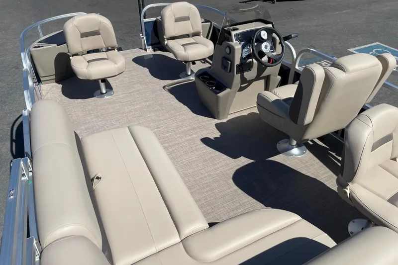 Slide: The Image of 2025 Sun Tracker Bass Buggy 18 DLX pontoon boat interior with beige seating and steering console. - 4
