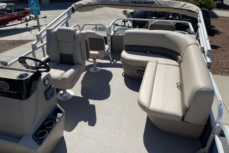Slide: The Image of 2025 Sun Tracker Bass Buggy 18 DLX pontoon boat interior with beige seating and steering console. - 5