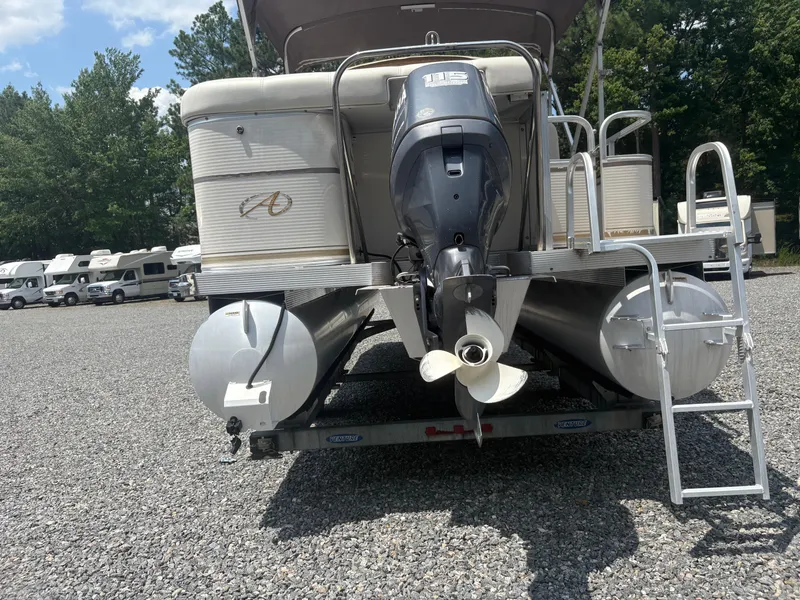 Slide: The Image of 2009 Avalon Paradise 24' pontoon boat with outboard motor in a parking lot. - 2