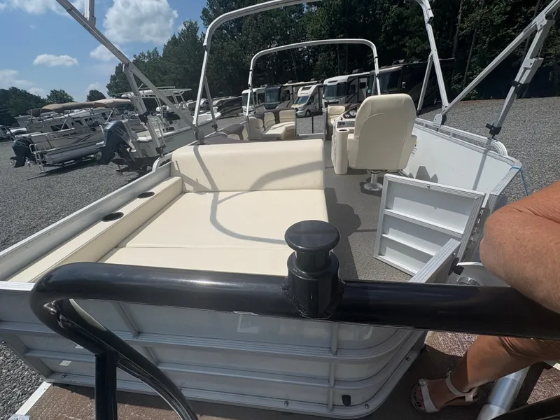 Slide: The Image of 2021 Lexington 321 pontoon boat with beige seating, parked outdoors under a blue sky. - 21