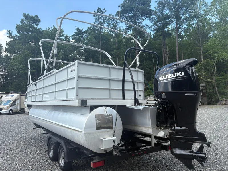 Slide: The Image of 2021 Lexington 321 pontoon boat with Suzuki outboard motor, parked on gravel lot. - 4