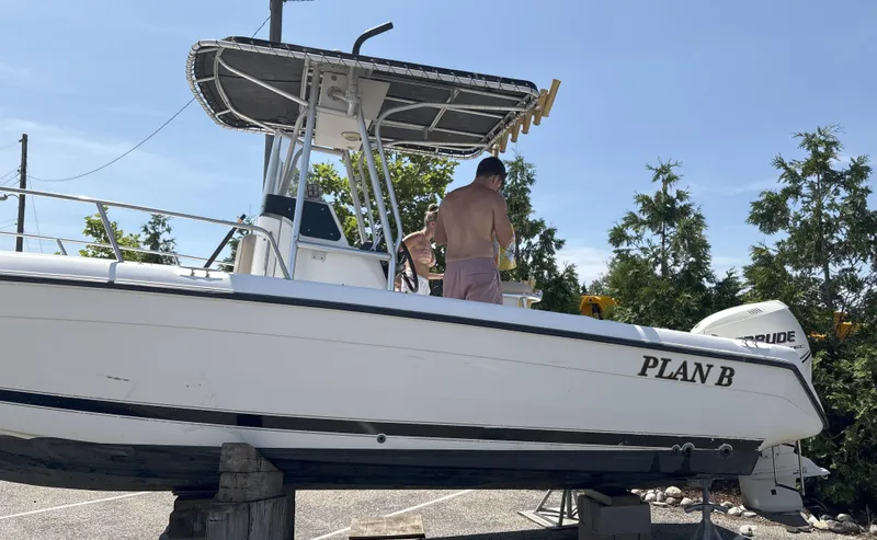 Slide: The Image of 1999 Century 2300 Center Console boat named "Plan B" on dry dock with people onboard. - 10