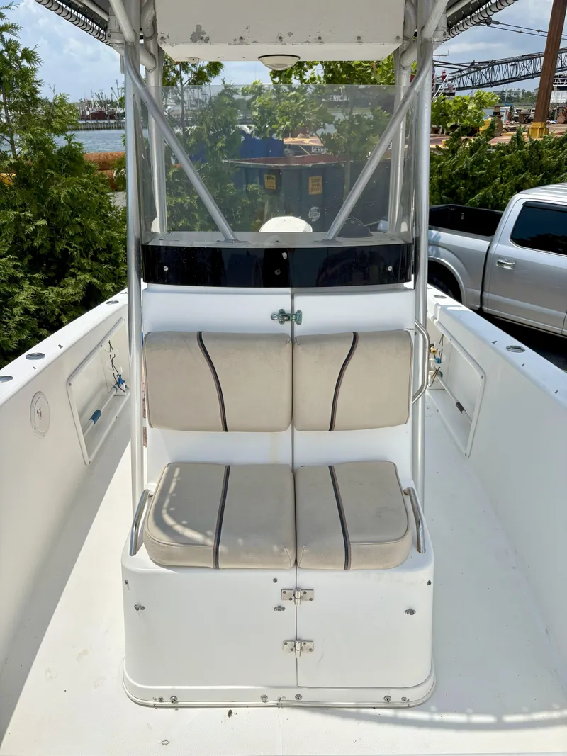 Slide: The Image of 1999 Century 2300 Center Console boat with dual seats and storage, docked near greenery. - 15