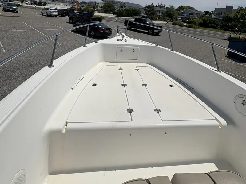 Slide: The Image of 1999 Century 2300 Center Console boat in parking lot, showcasing spacious deck and storage compartments. - 16