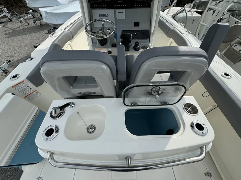 Slide: The Image of 2025 Boston Whaler 280 Outrage boat interior with helm, sink, and storage compartments. - 17