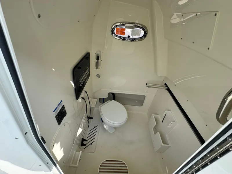 Slide: The Image of 2025 Boston Whaler 280 Outrage interior cabin with toilet and porthole window. - 24