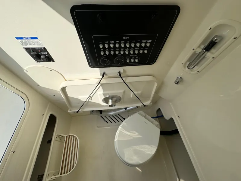 Slide: The Image of Interior of 2025 Boston Whaler 280 Outrage boat, featuring a compact marine toilet. - 25