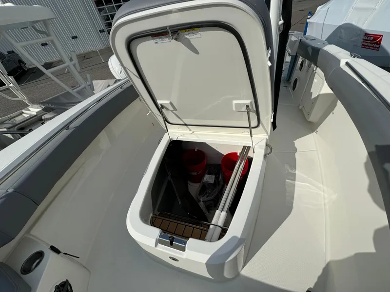 Slide: The Image of 2025 Boston Whaler 280 Outrage storage compartment with open hatch, revealing interior equipment. - 29