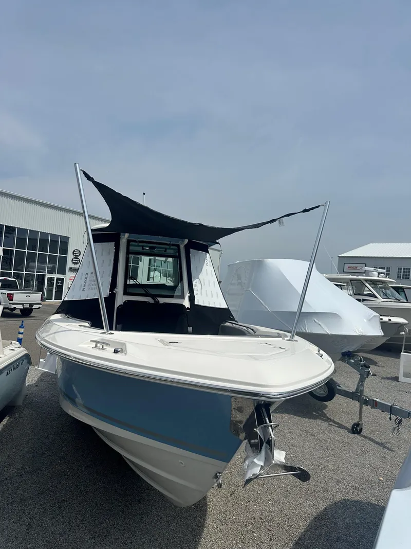 Slide: The Image of 2025 Boston Whaler 280 Outrage boat displayed outdoors with canopy and trailer. - 35
