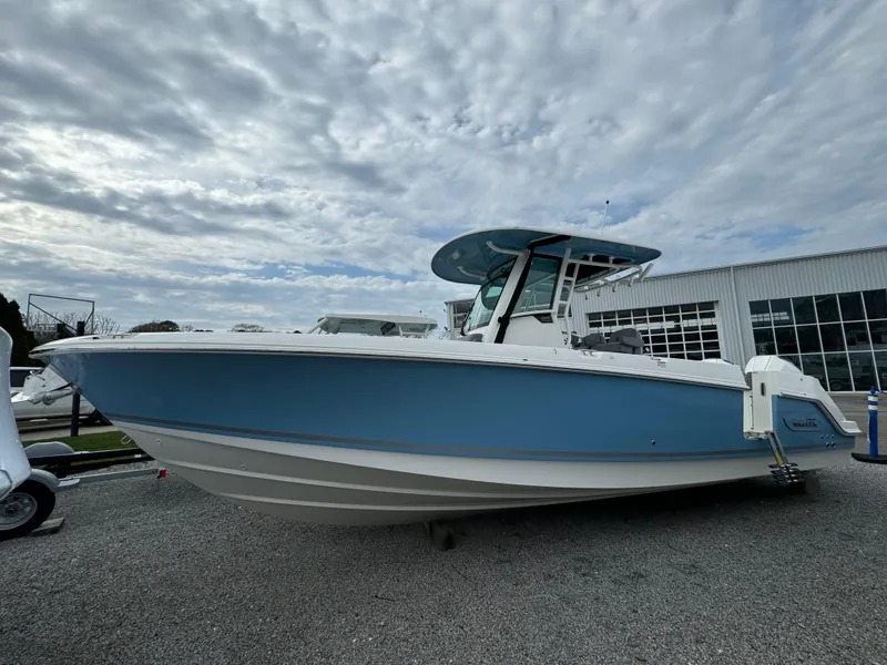 Slide: The Image of 2025 Boston Whaler 280 Outrage boat with blue hull, displayed outdoors under cloudy sky. - 38