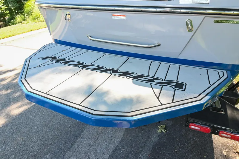 Slide: The Image of 2021 Moomba Kaiyen boat swim platform with logo, parked on pavement. - 11