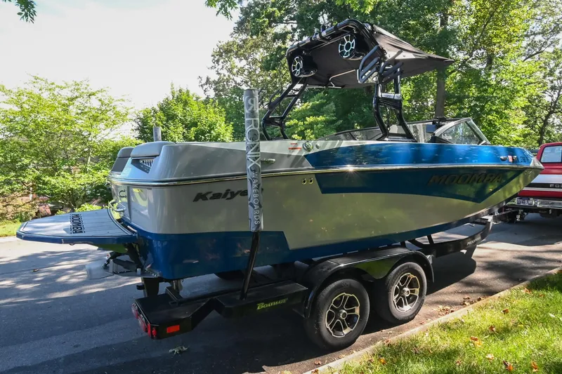 Slide: The Image of 2021 Moomba Kaiyen boat on trailer, parked outdoors, surrounded by trees. - 4