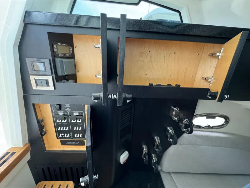 Slide: The Image of Interior view of 2025 Boston Whaler 380 Outrage, featuring control panel and storage compartments. - 22