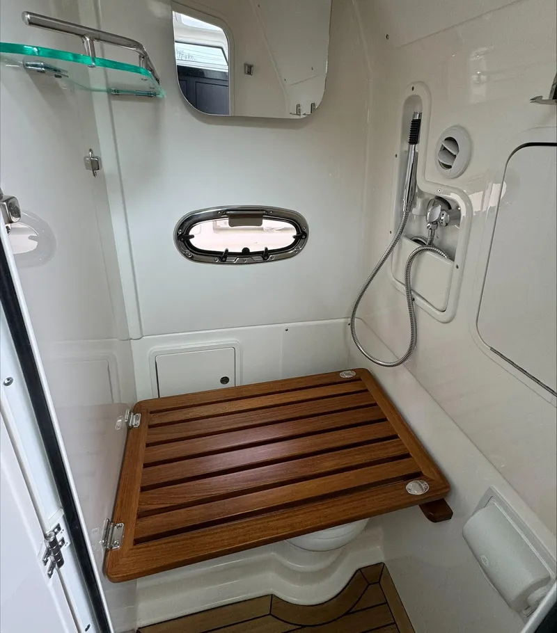 Slide: The Image of 2025 Boston Whaler 380 Outrage bathroom with wooden seat and showerhead. - 28