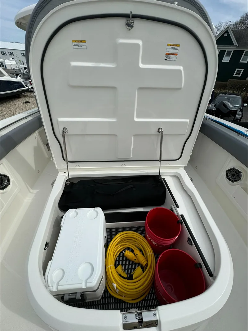 Slide: The Image of 2025 Boston Whaler 380 Outrage storage compartment with cooler, hose, and buckets. - 38
