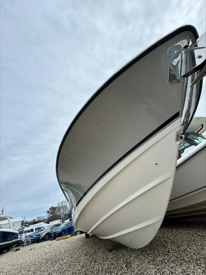 Slide: The Image of 2025 Boston Whaler 380 Outrage boat hull on gravel, showcasing sleek design. - 44
