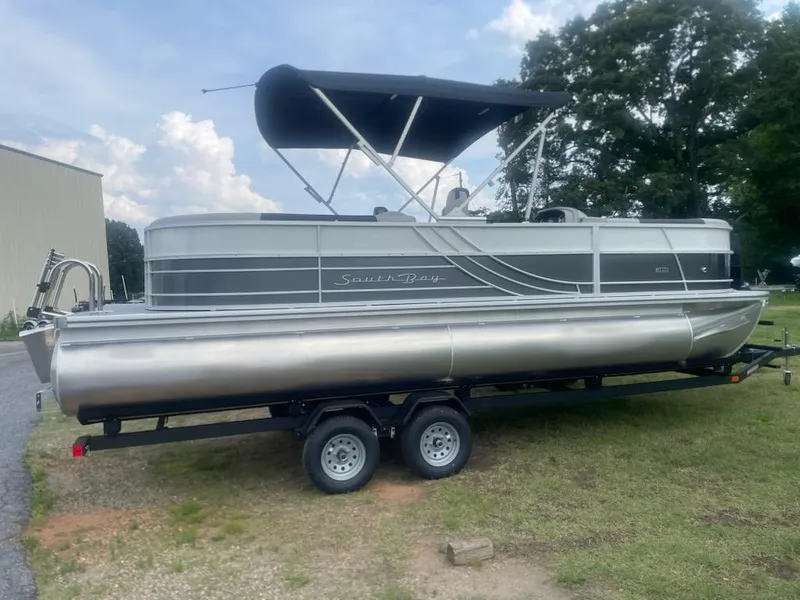 Slide: The Image of 2025 South Bay 224RS LE 2.75 pontoon boat on trailer, parked outdoors. - 1