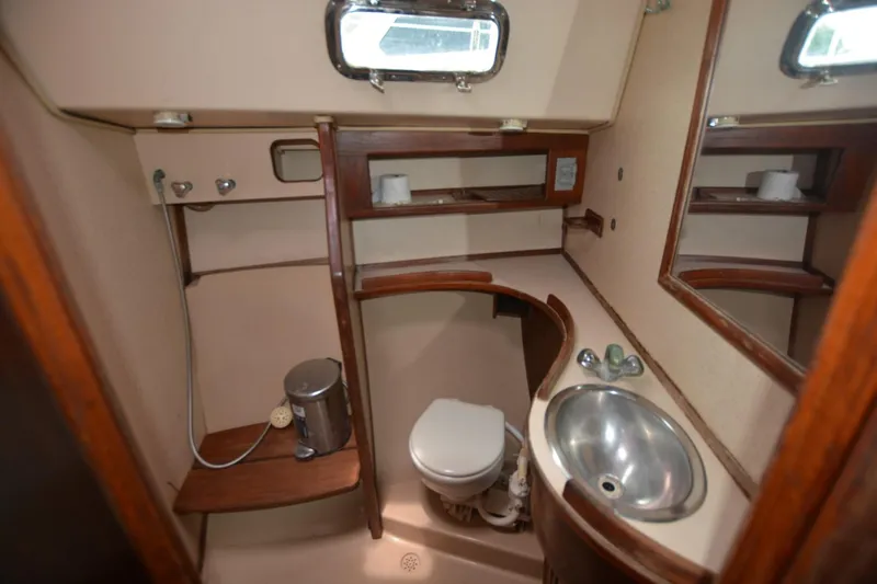 Slide: The Image of 1994 Island Packet 44 yacht bathroom with sink, toilet, mirror, and wooden accents. - 14