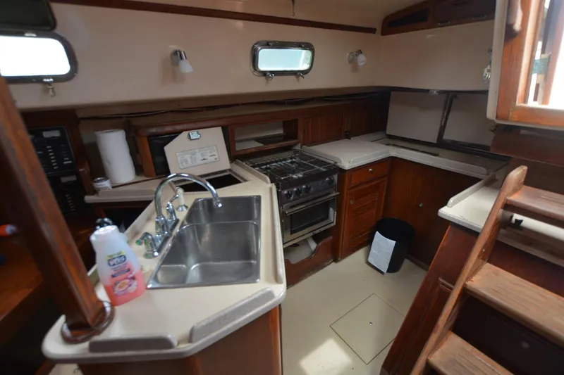Slide: The Image of 1994 Island Packet 44 yacht kitchen with sink, stove, and wooden cabinetry. - 19