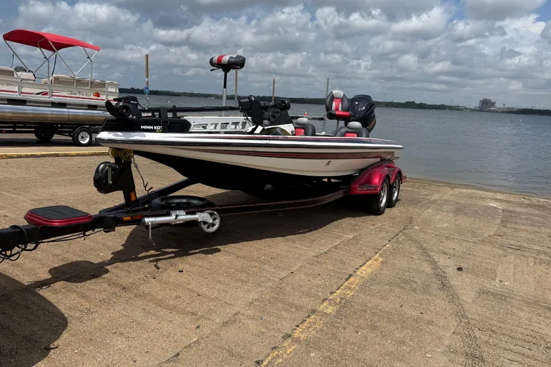 Slide: The Image of 2011 Skeeter FX 21 boat on trailer by a lake under cloudy sky. - 0