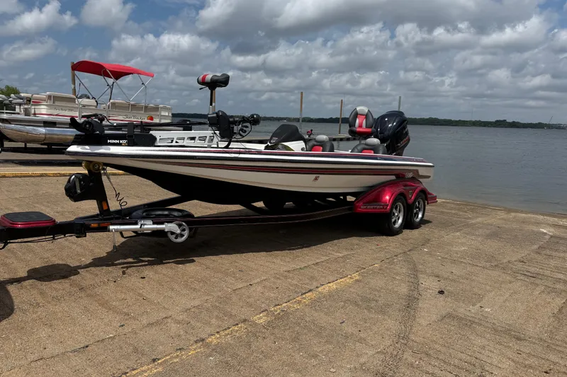 Slide: The Image of 2011 Skeeter FX 21 boat on trailer by a lake under cloudy sky. - 1