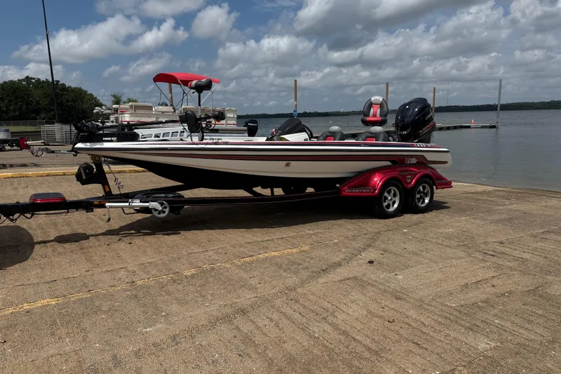 Slide: The Image of 2011 Skeeter FX 21 boat on trailer by a lake under cloudy sky. - 2