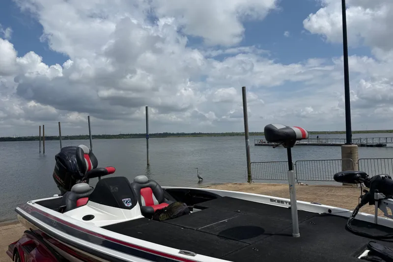 Slide: The Image of 2011 Skeeter FX 21 boat docked by a serene lake under a cloudy sky. - 20