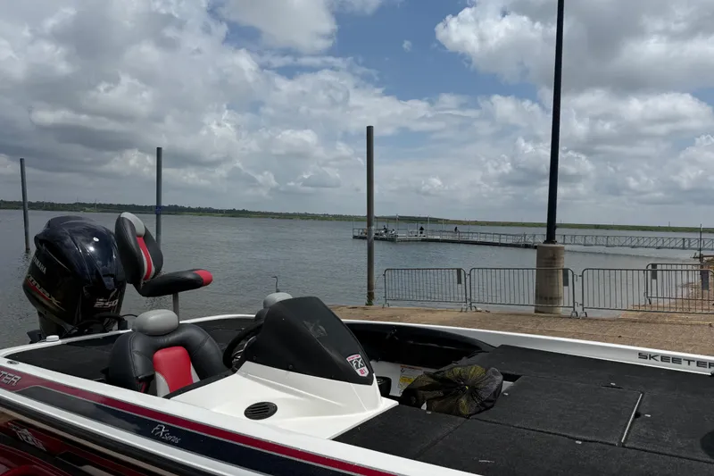Slide: The Image of 2011 Skeeter FX 21 boat docked by a lake under a cloudy sky. - 21