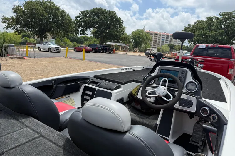 Slide: The Image of 2011 Skeeter FX 21 boat interior with steering wheel and dashboard, parked outdoors. - 23