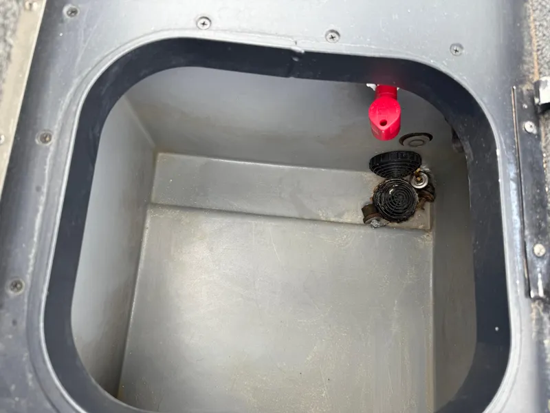 Slide: The Image of Open storage compartment in 2011 Skeeter FX 21 boat, featuring drainage and red valve. - 41