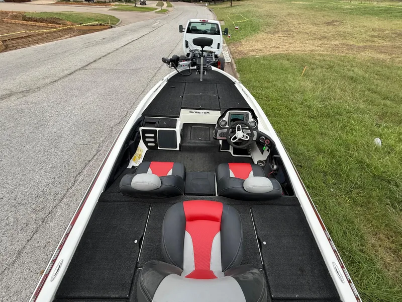 Slide: The Image of 2011 Skeeter FX 21 bass boat with red and gray seats, parked on roadside. - 46