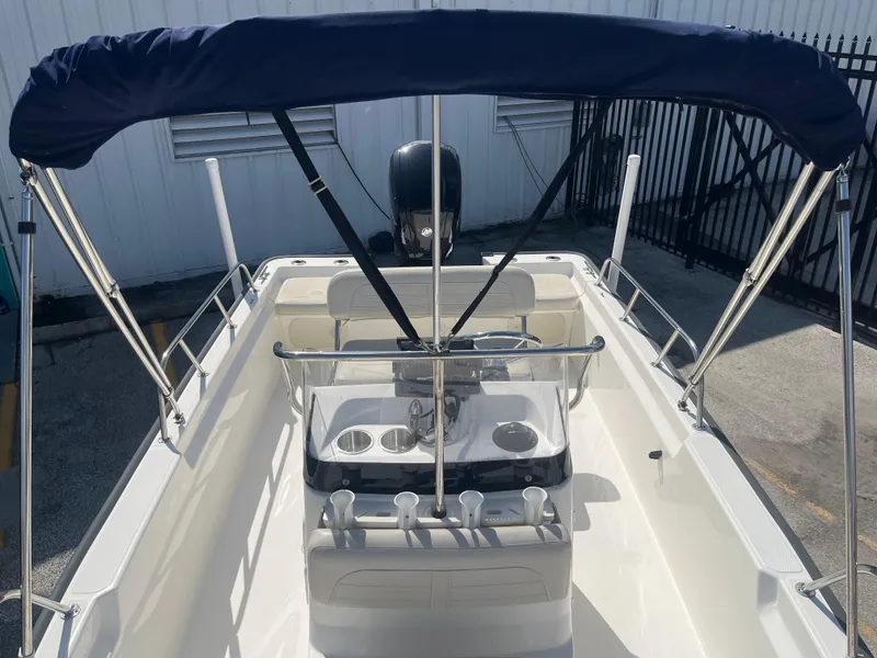 Slide: The Image of 2022 Boston Whaler 170 Montauk boat with canopy and console, docked outdoors. - 6