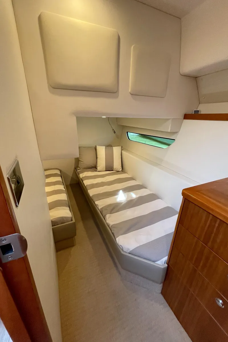 Slide: The Image of 2017 Riviera 3600 Sport Yacht cabin with twin beds and striped bedding. - 41