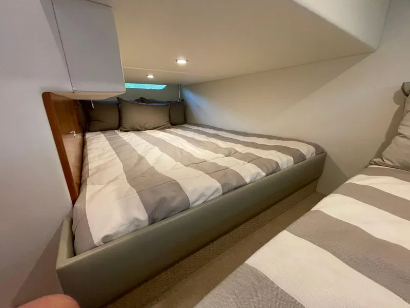 Slide: The Image of Cozy bedroom in 2017 Riviera 3600 Sport Yacht with striped bedding and soft lighting. - 42