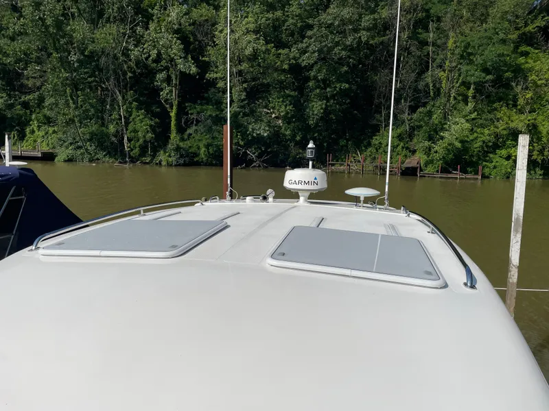 Slide: The Image of 2017 Riviera 3600 Sport Yacht with Garmin equipment, docked by a lush, wooded shoreline. - 49