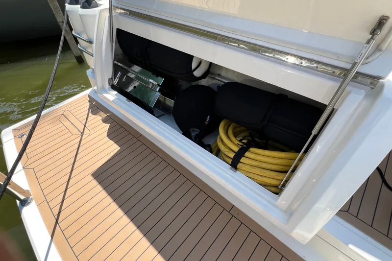 Slide: The Image of 2017 Riviera 3600 Sport Yacht storage compartment with coiled yellow hose and equipment. - 58
