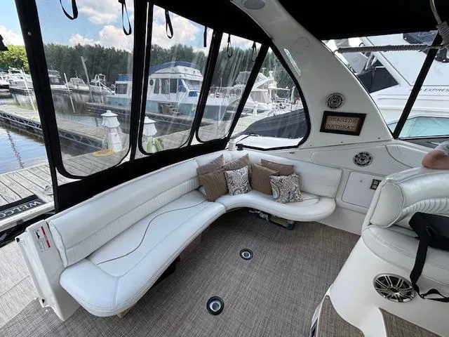Slide: The Image of 1998 Cruisers Yachts 3575 Express interior with white seating and decorative pillows at marina. - 3