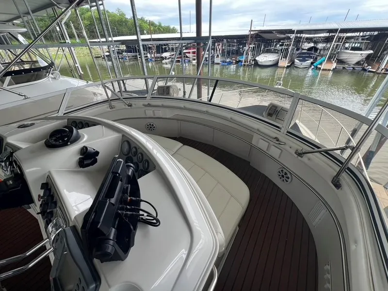 Slide: The Image of 1998 Carver 455 Aft Cabin Motoryacht helm with marina view, featuring modern controls and seating. - 47