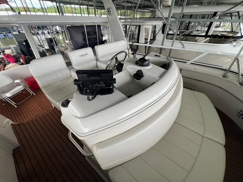 Slide: The Image of 1998 Carver 455 Aft Cabin Motoryacht helm with white seating and wooden deck. - 48
